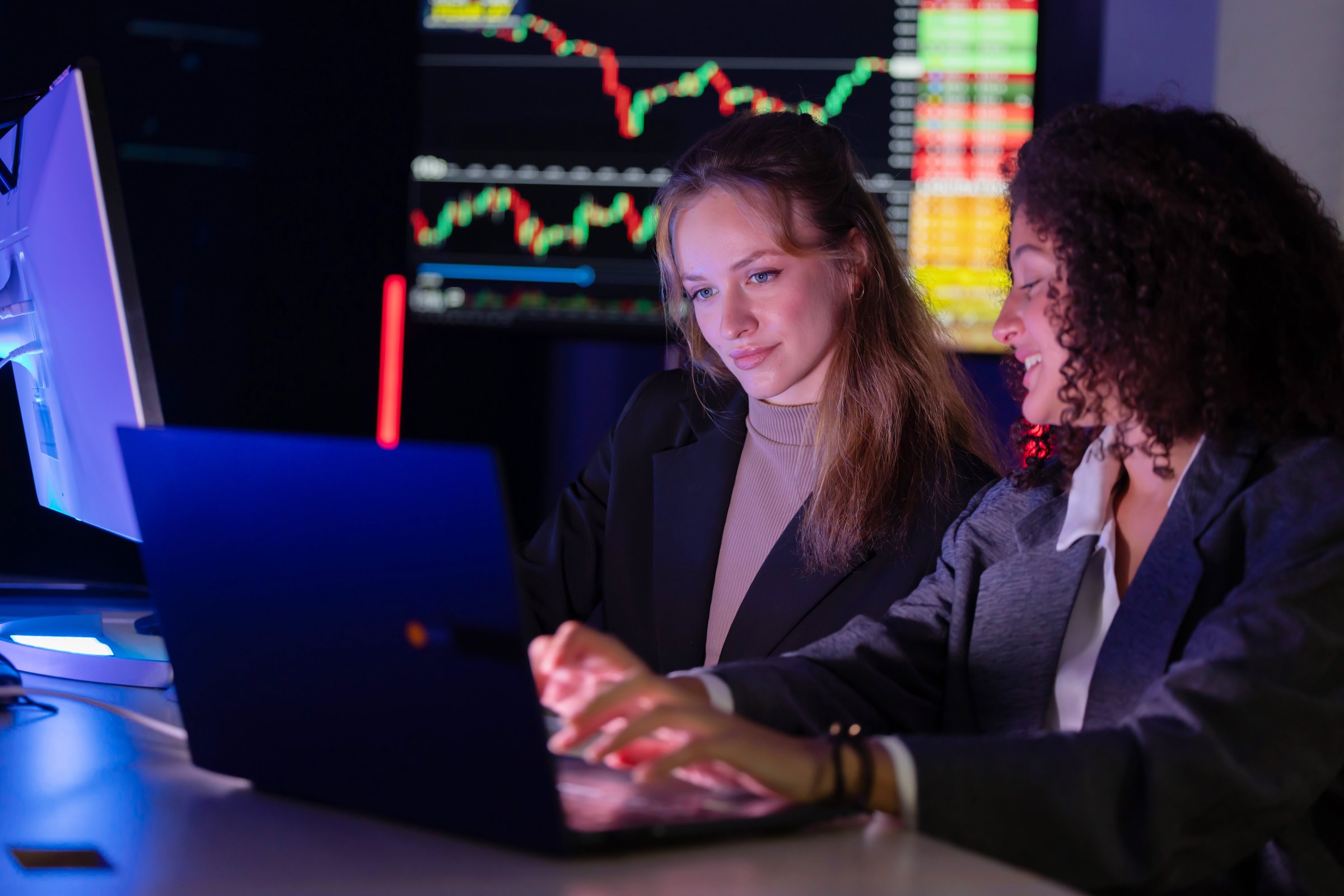 Caucasian colleagues in a focused discussion about stock market trends in a modern office setting during evening hours