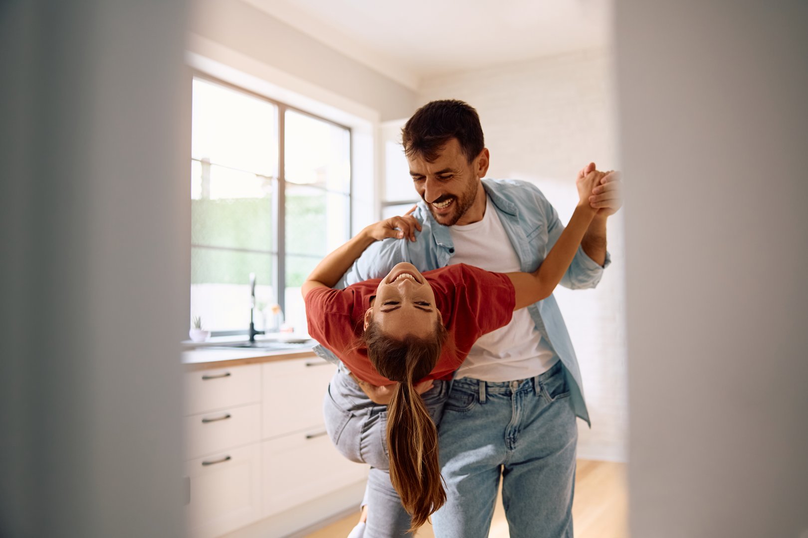 Carefree woman and her boyfriend dancing in the kitchen.