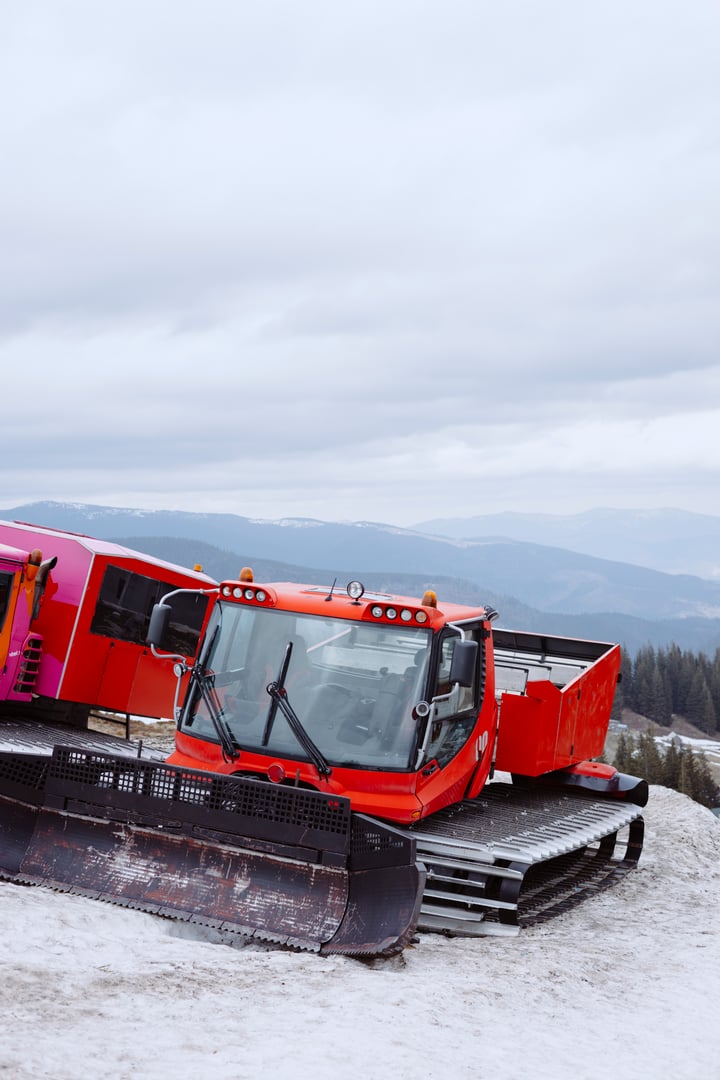 Machine for skiing slope preparations at background of mountains. Snowplow machine at snowy ski resort.