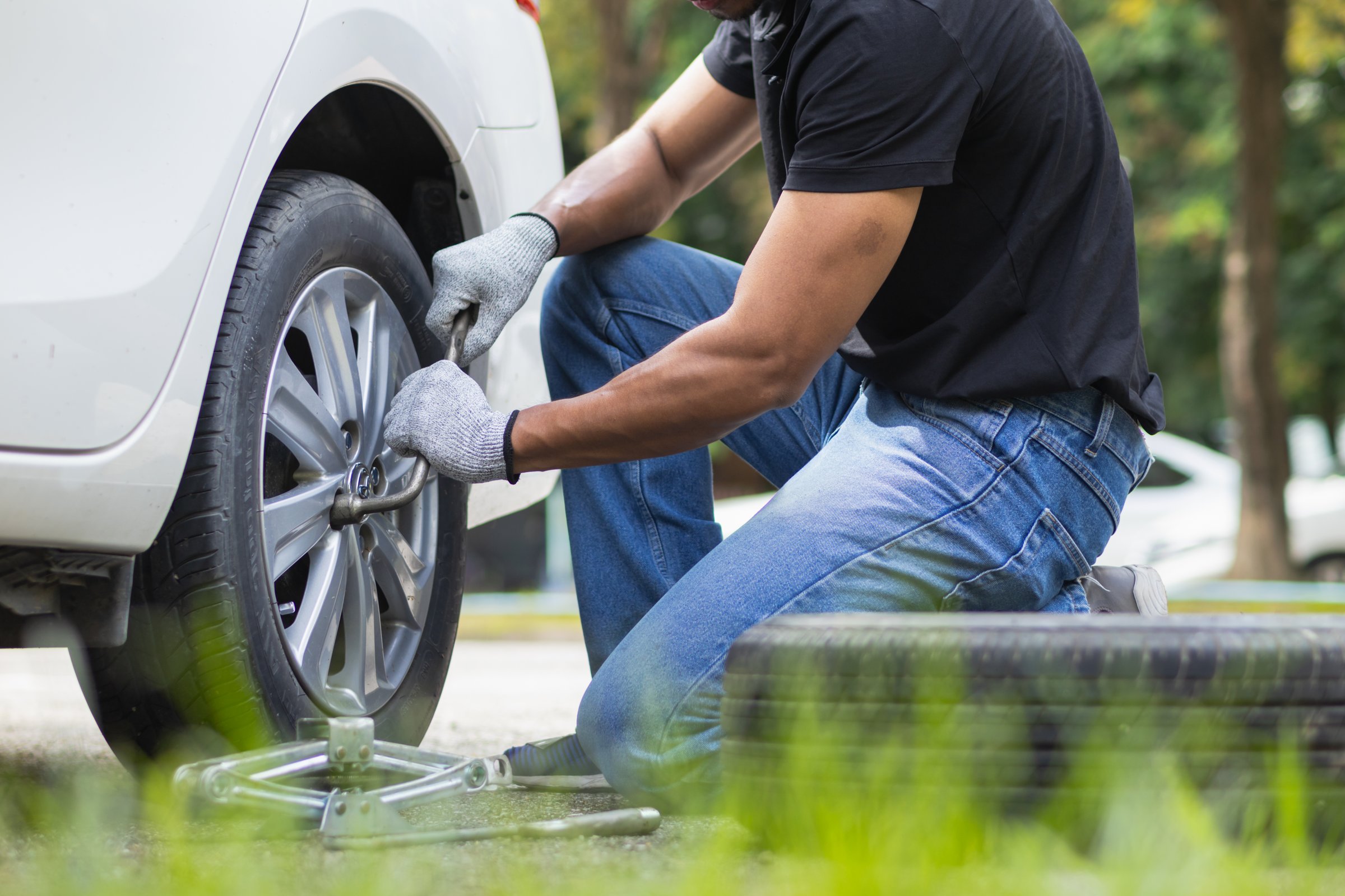 mechanic is preparing the equipment and spare tire to change the tire of the car that had a flat tire during the journey and the mechanic was called by the emergency application of the service center.