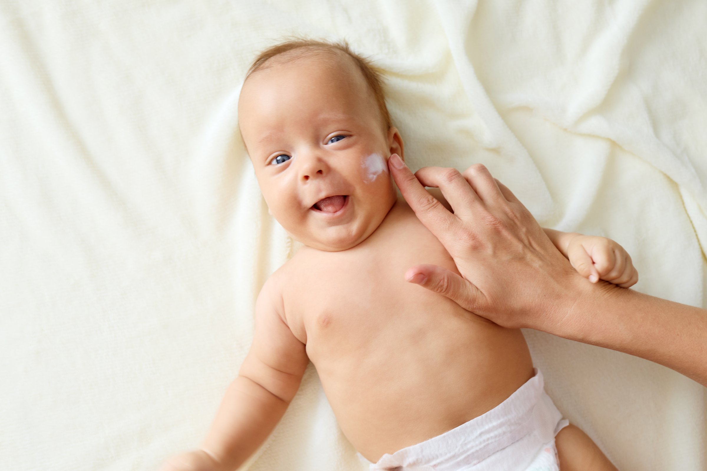 Mother applying lotion to her newborn's cheeks