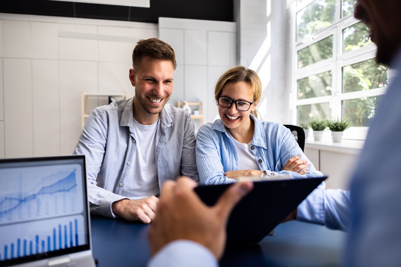 Financial consultant explaining new project investment to young couple in office. Real estate agent discussing mortgage options with family. Mortgage loan consultation with financial advisor.