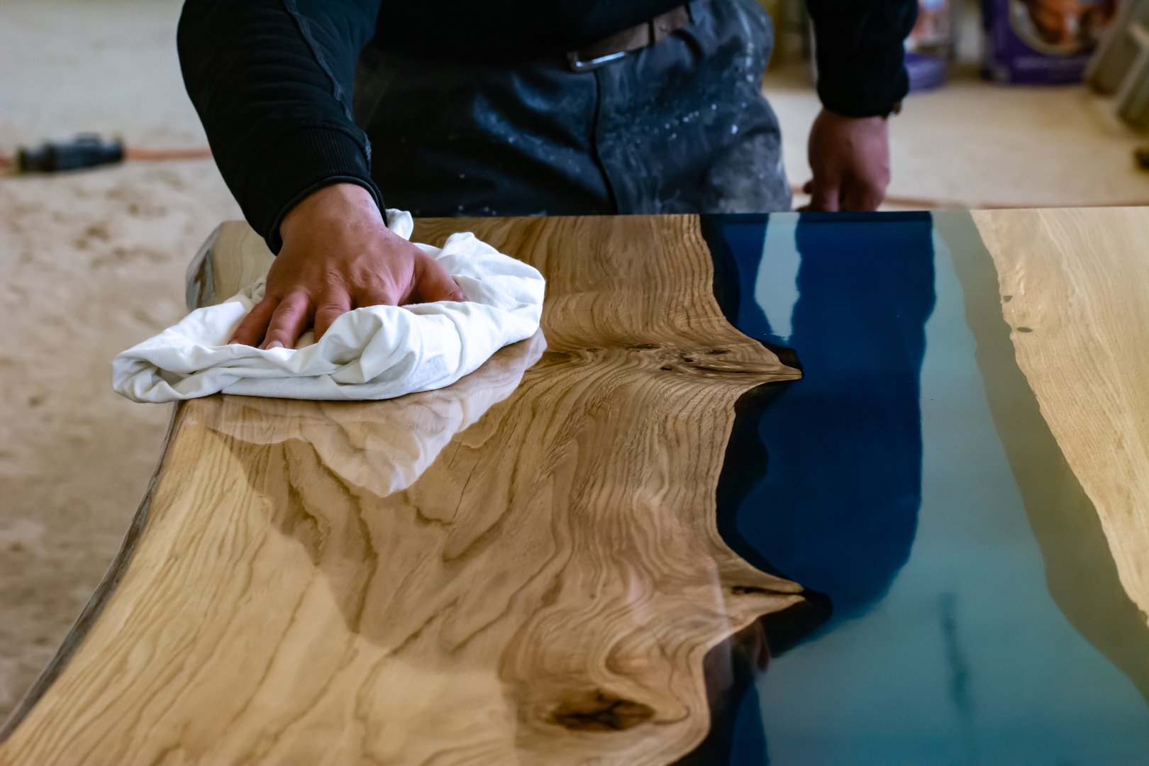 Wiping the remains of the polishing paste on the oak and epoxy resin table