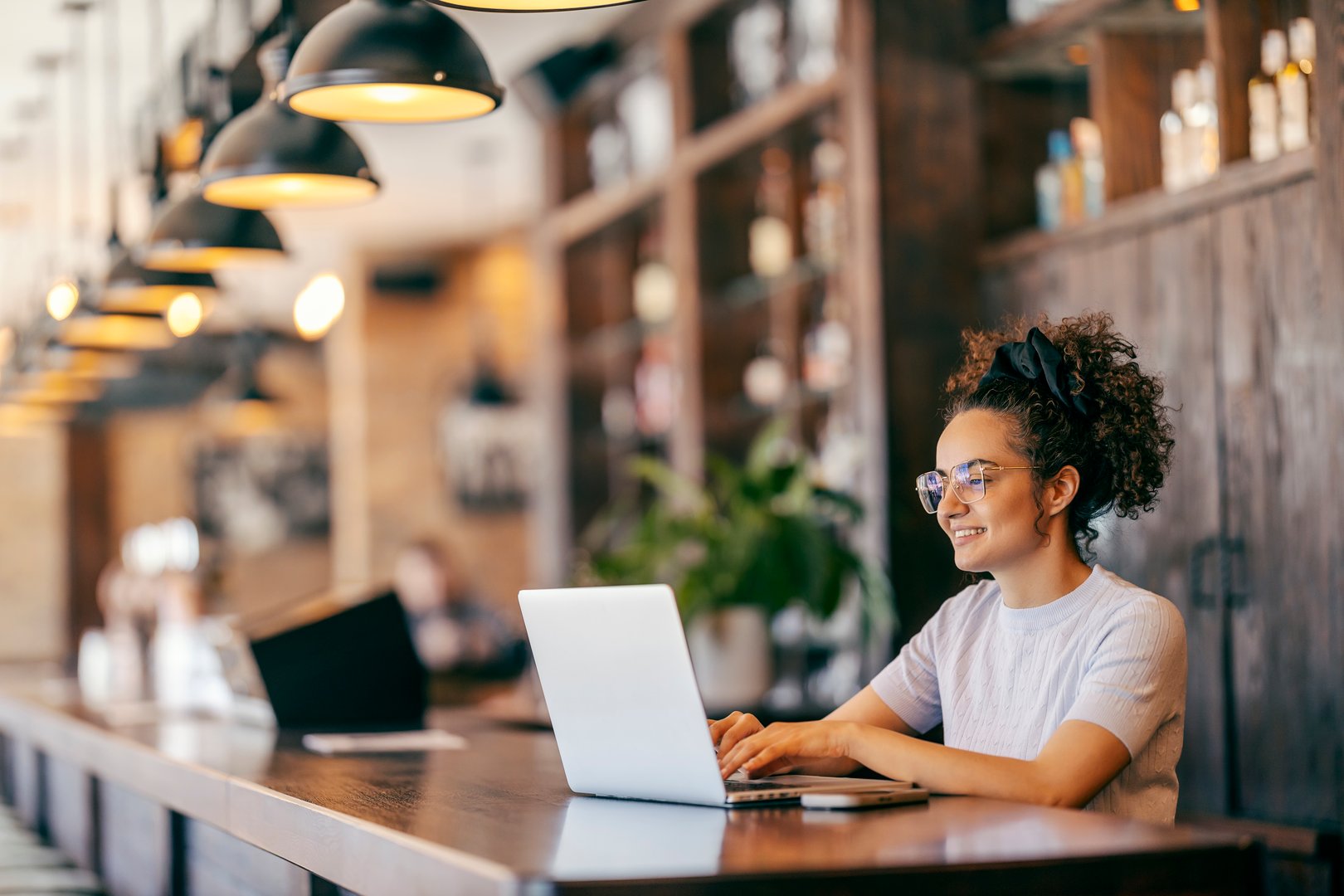 Smiling dedicated freelancer sitting in cafe and typing on a laptop.