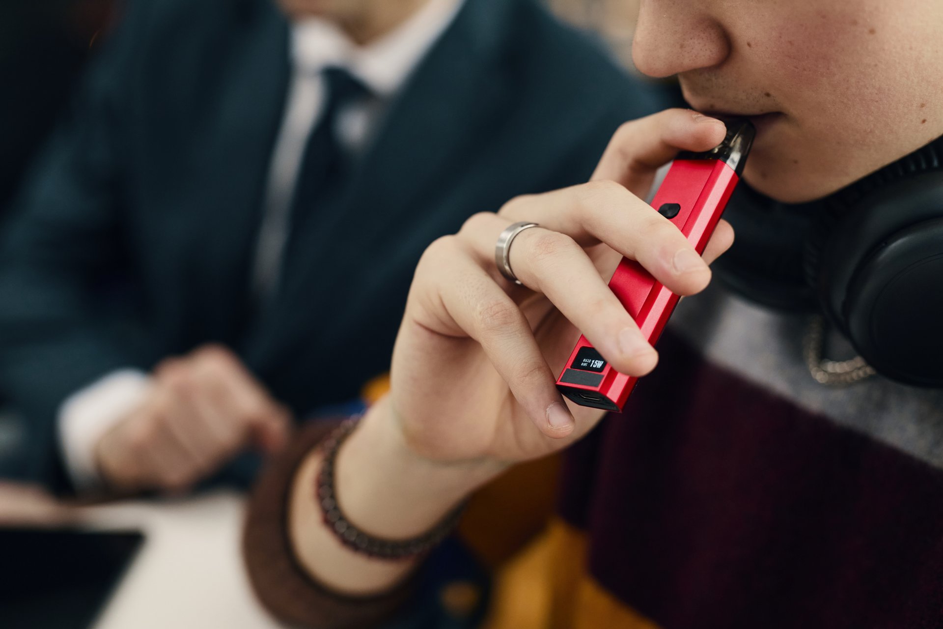 Close-up of employee smoking electronic cigarette at work in office