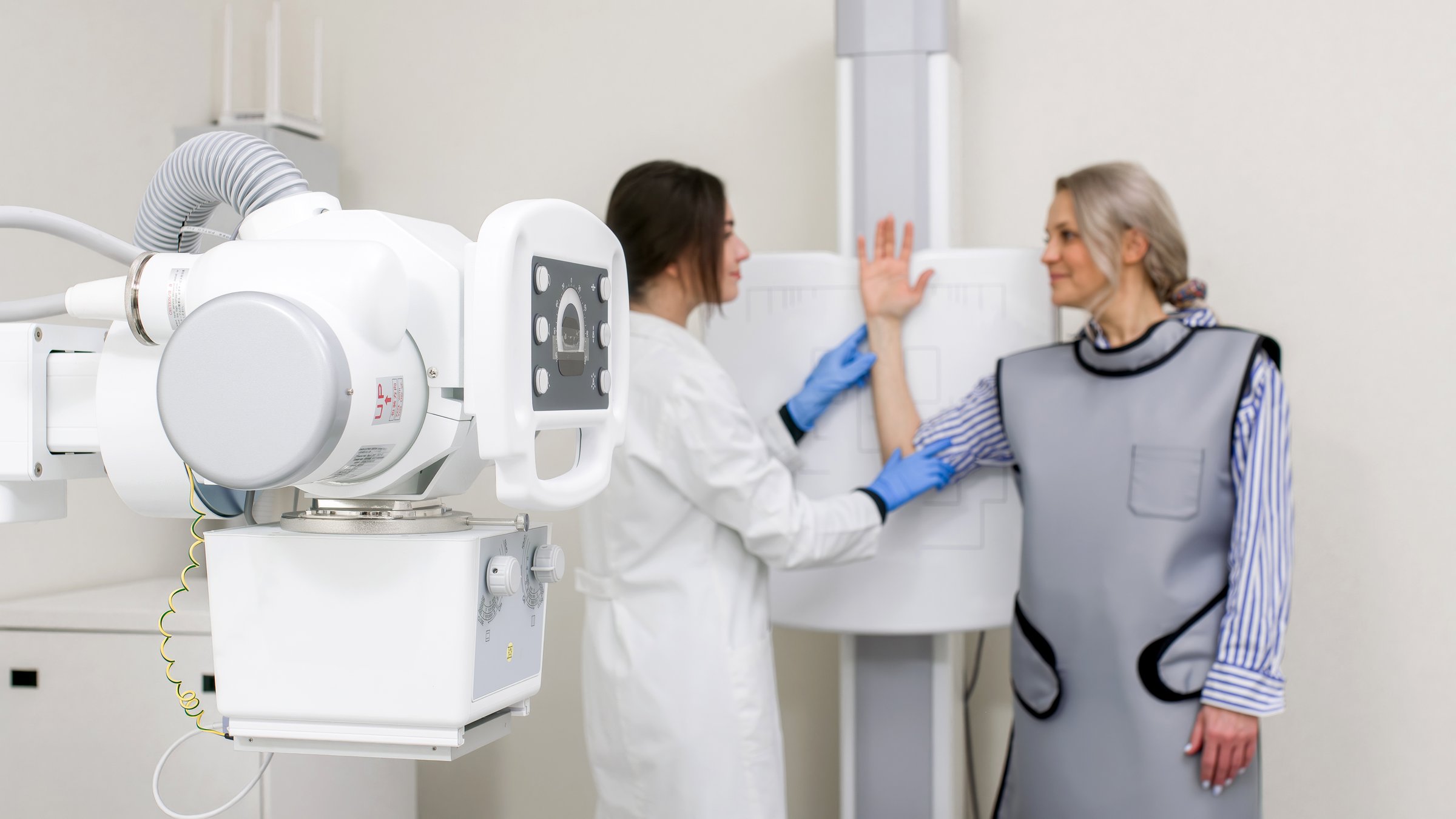 A specialist doctor in an X-ray room, a radiologist sets up a machine for radiography of a patient and makes a scan. The concept of medical technologies, modern medical equipment.