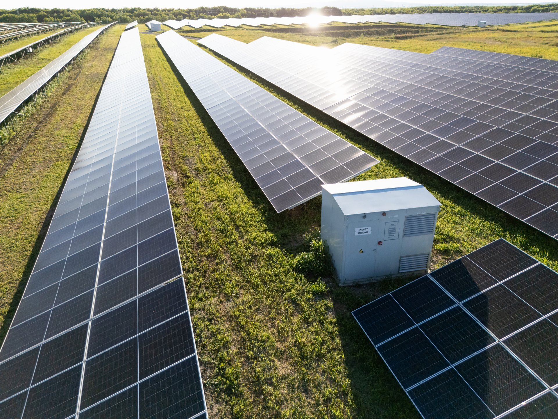 Drone point of view of agricultural field with photovoltaic power station. There are a lot of solar panels at sunset.