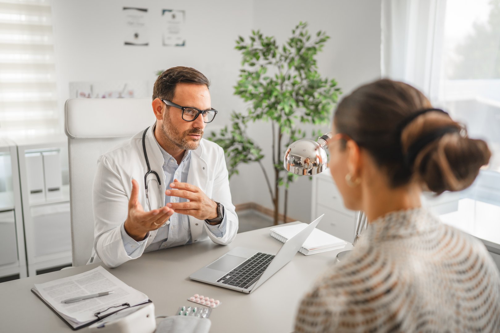 Male doctor explaining medical information and healthcare options to a female patient, emphasizing communication and trust during an office visit at a modern clinic