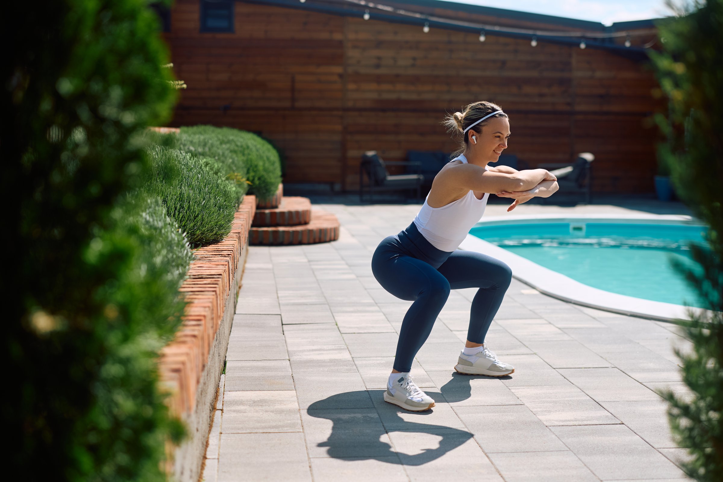Happy sportswoman exercising squats while working out outdoors. Copy space.