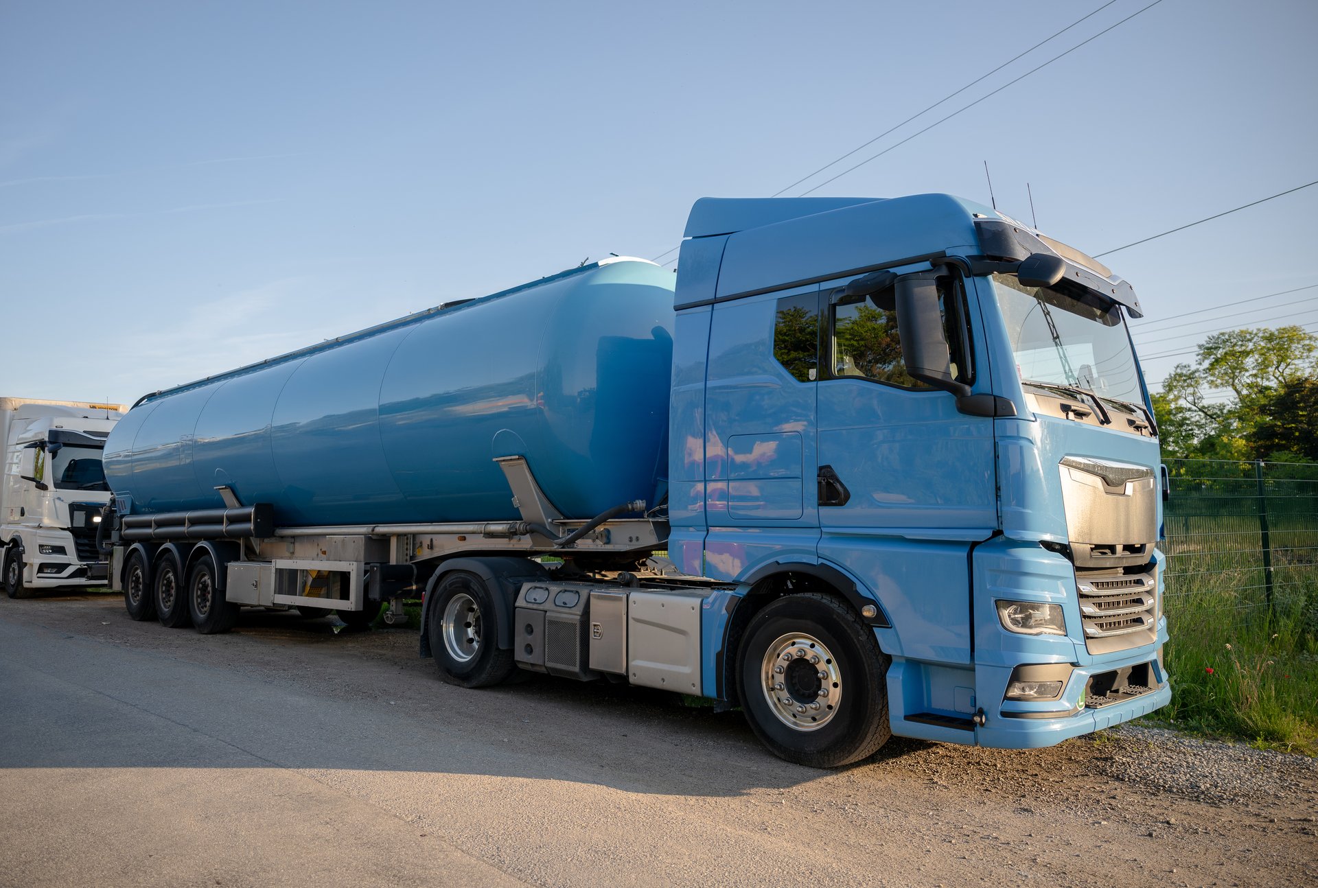 Semi truck with tanker parked near railway tracks at sunset