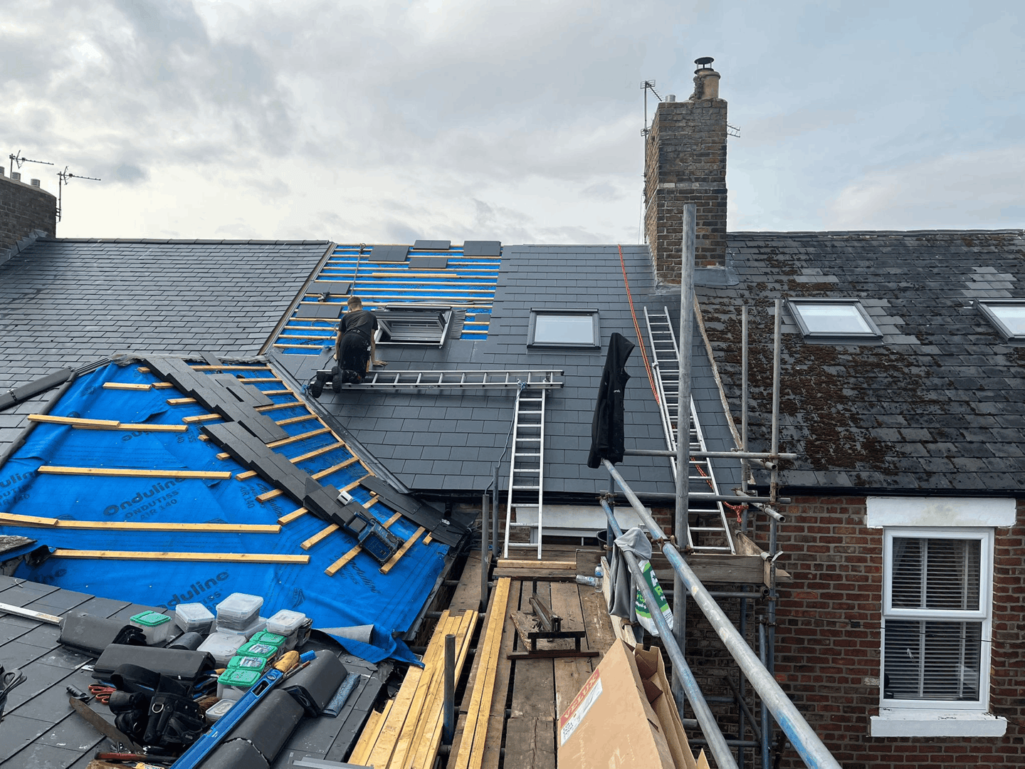 Professional UK roofers installing new slate roof on British home