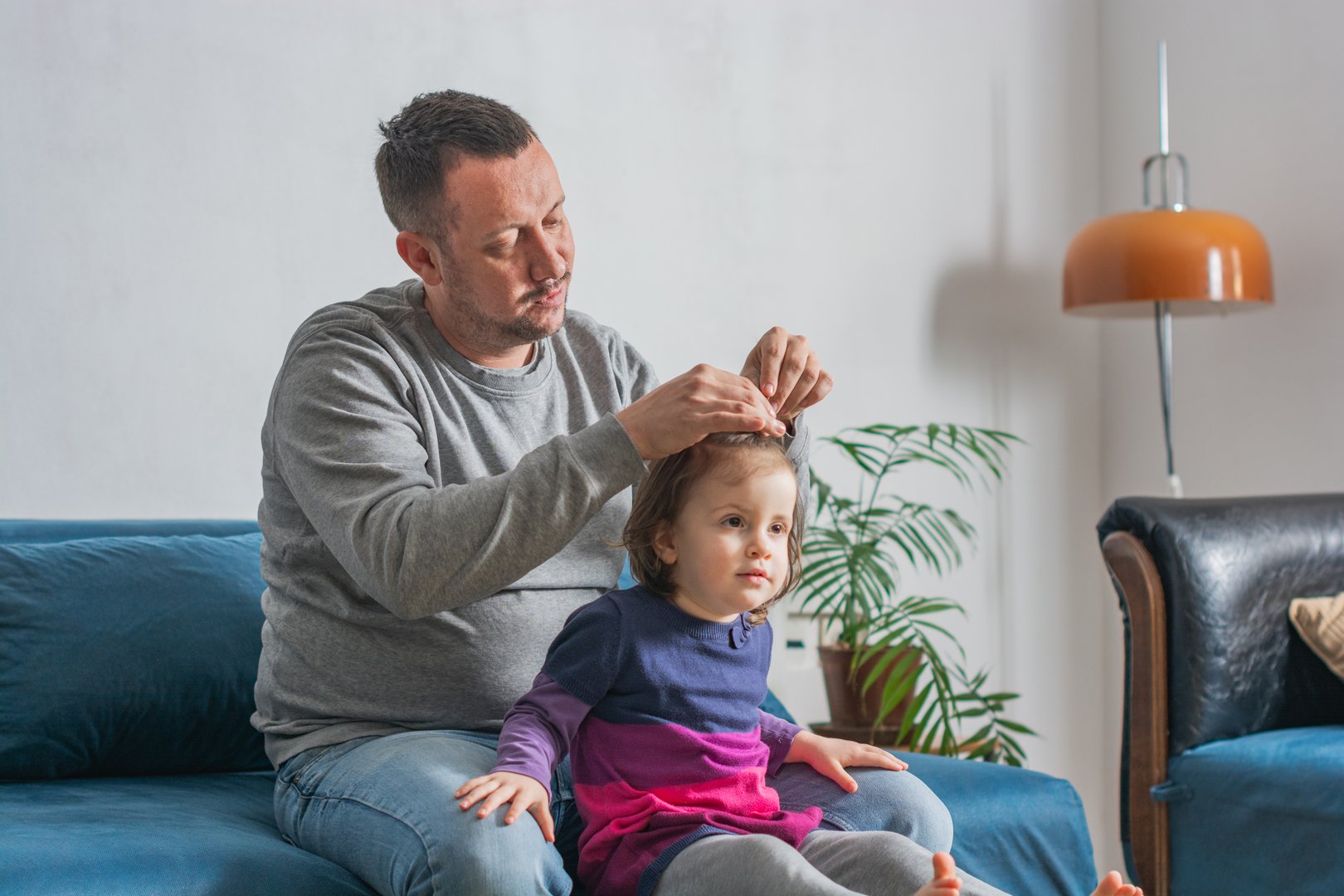 Happy father making a ponytail for his small daughter at home