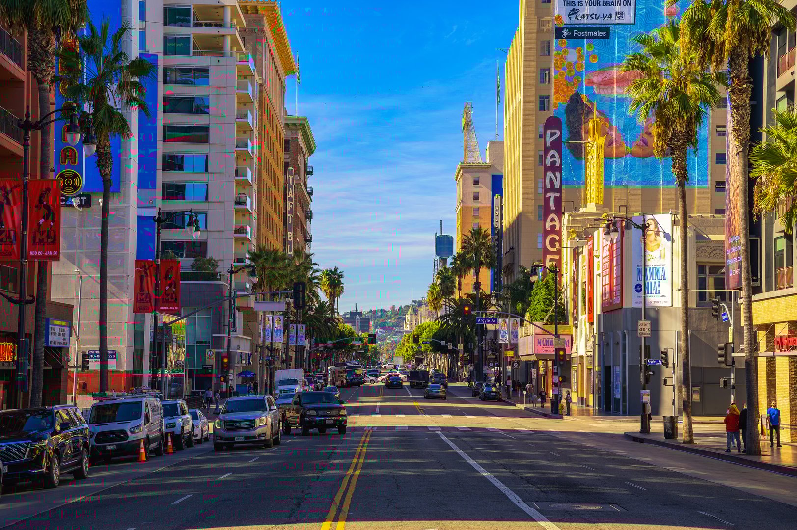 Hollywood, California, USA - November 14, 2023 : A sunny view of Hollywood Boulevard in Hollywood with palm trees, cars, and and iconic buildings like the Pantages Theatre.