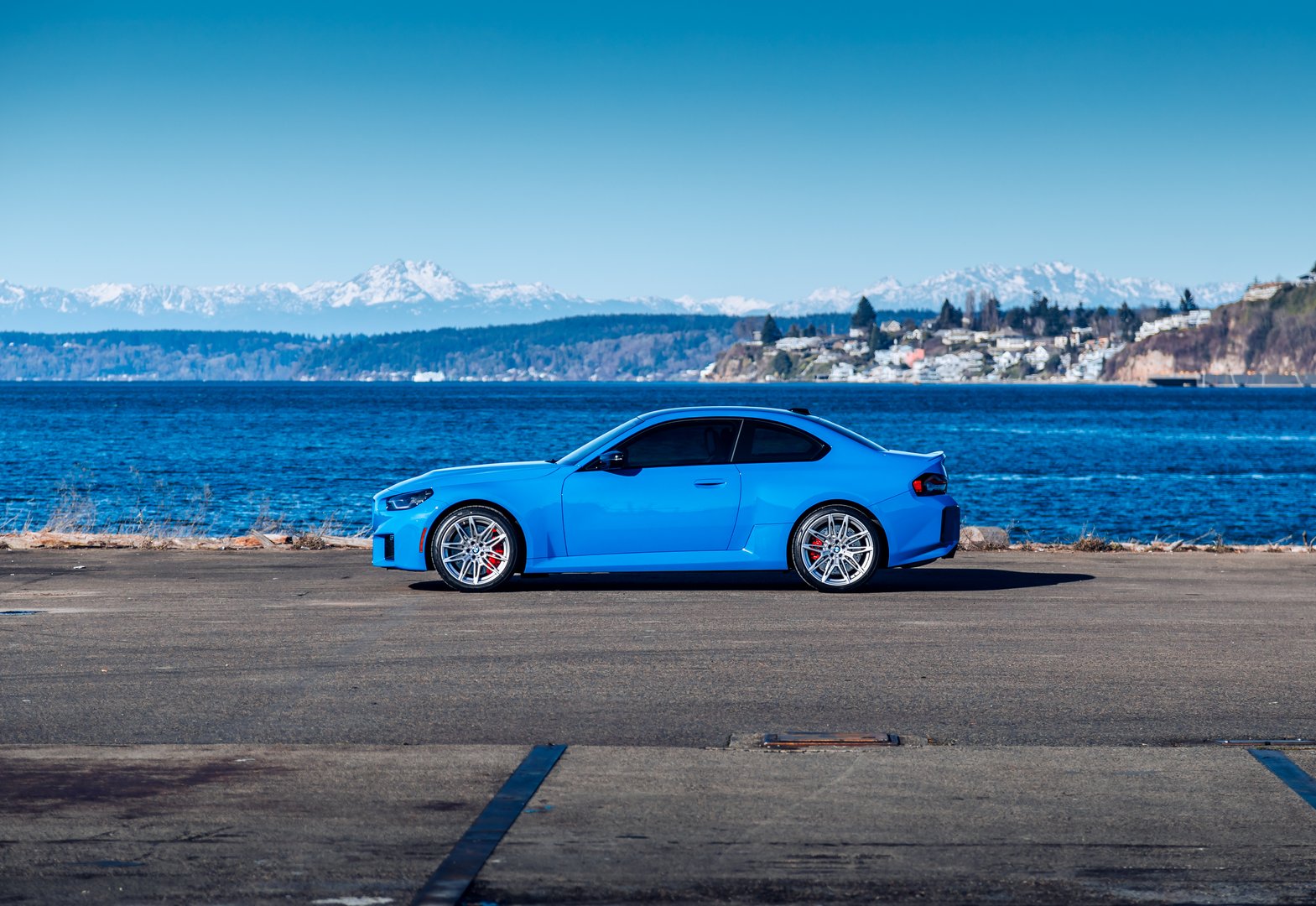 Seattle, WA, USAFebruary 7, 2025Blue BMW M2 parked showing the drivers side with water in the background
