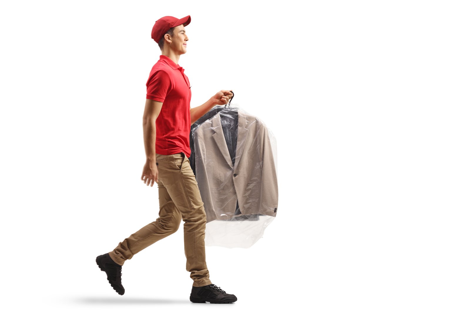 Young male dry clean worker carrying a suit on a hanger  isolated on white background