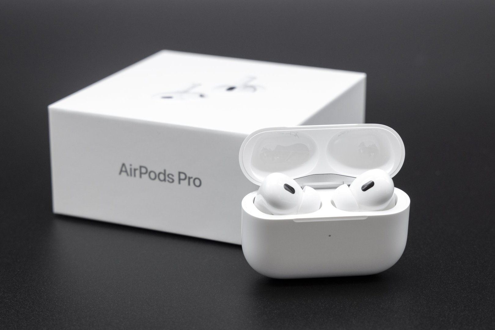 Germany – October 02, 2022: Product shot of Apple AirPods Pro 2nd generation inside the charging case next to the packaging box. Dark background.
