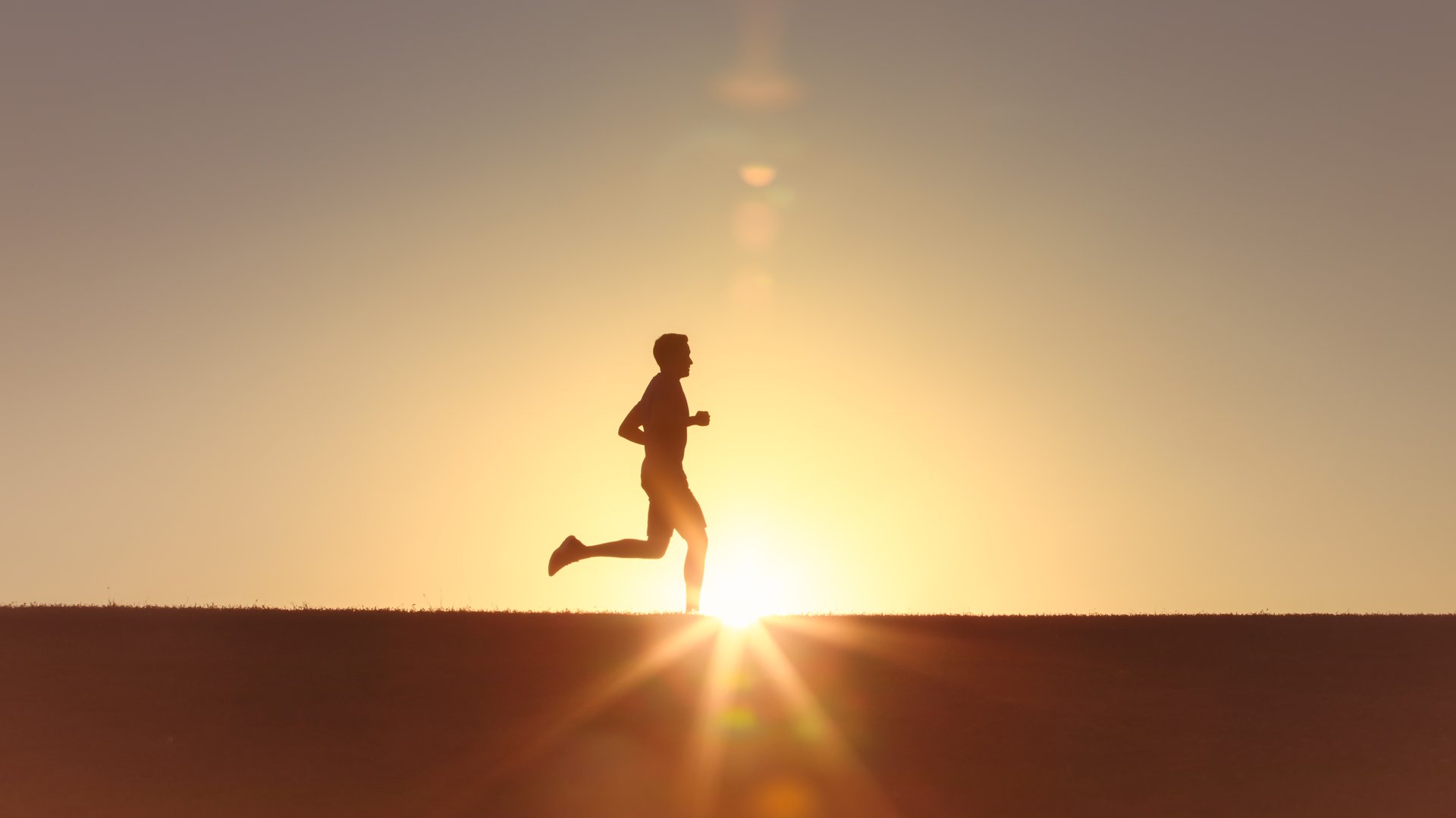 Persona corriendo al amanecer, silhouette contra luz dorada, libertad y movimiento