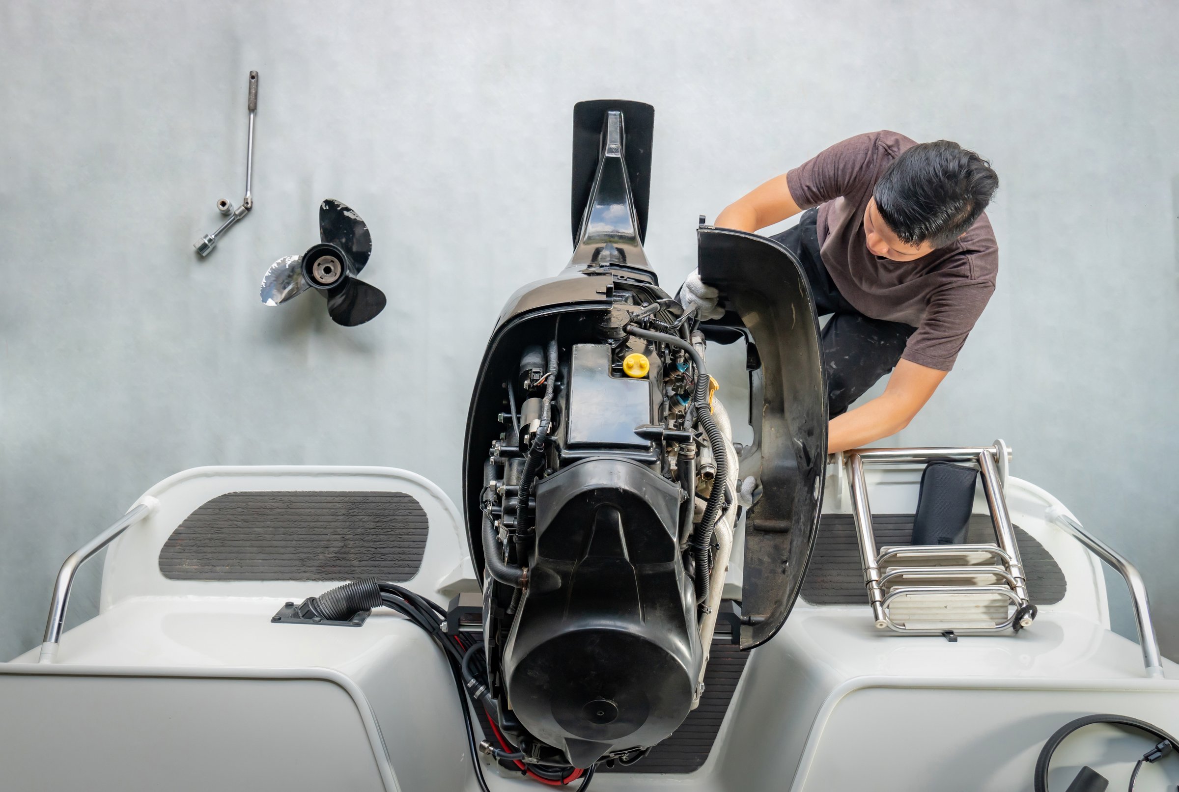 Repairing engines on aluminum boats , The technician is removing the boat parts to make the paint