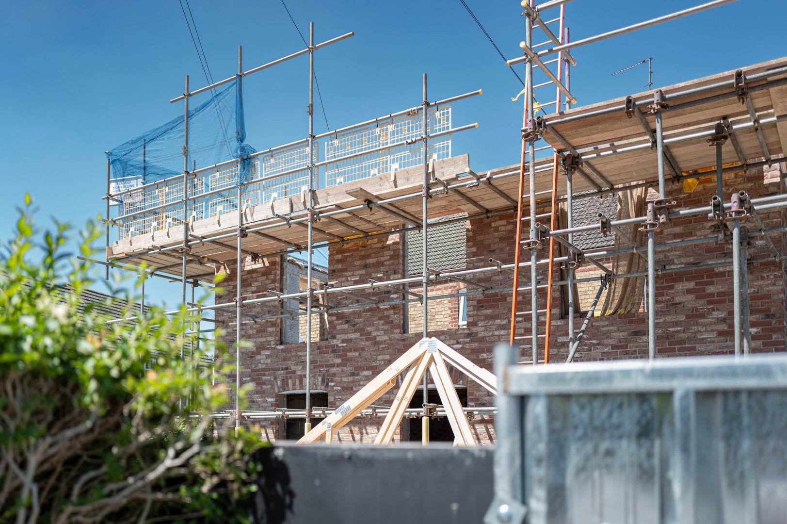 In progress first floor housing extension. Showing the scaffolding and soon to be fitted timber roof seen laying next to the build.
