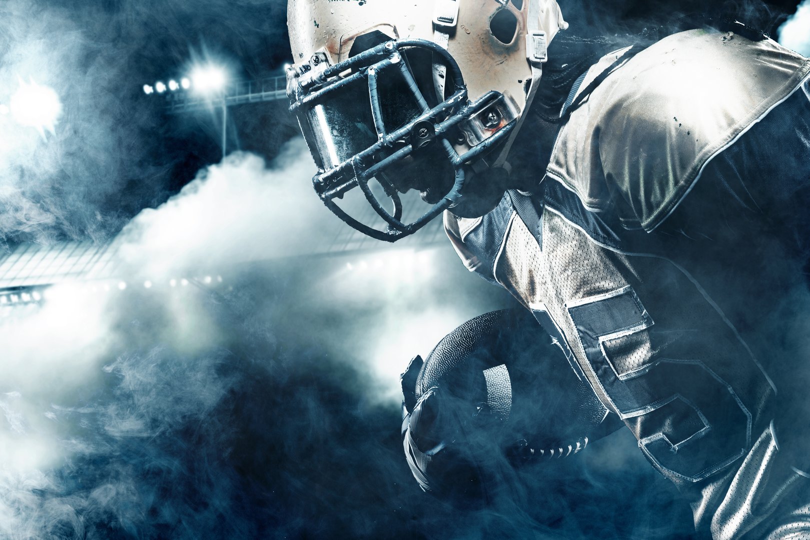 American Football player on stadium with smoke and lights.