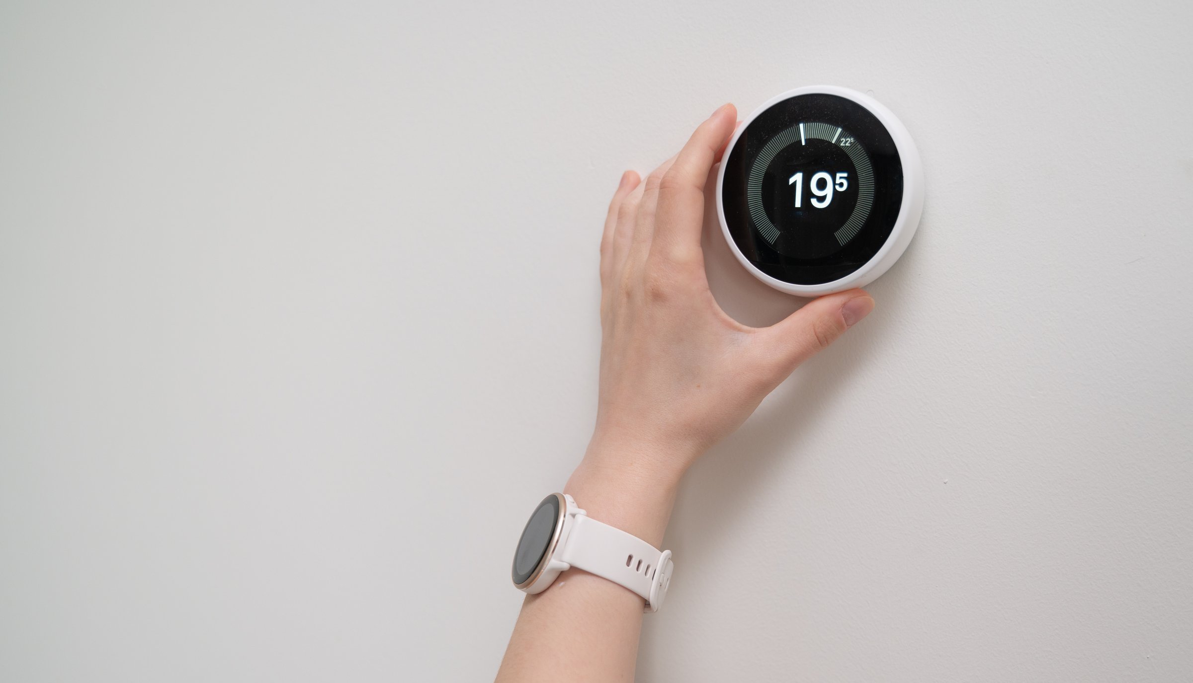 A hand adjusting a smart thermostat displaying 19C for energy efficiency