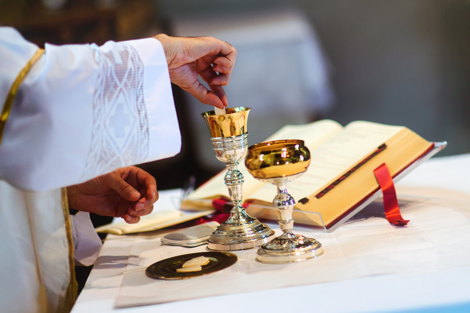 Priest draws consecrated host in wine for Eucharist in church