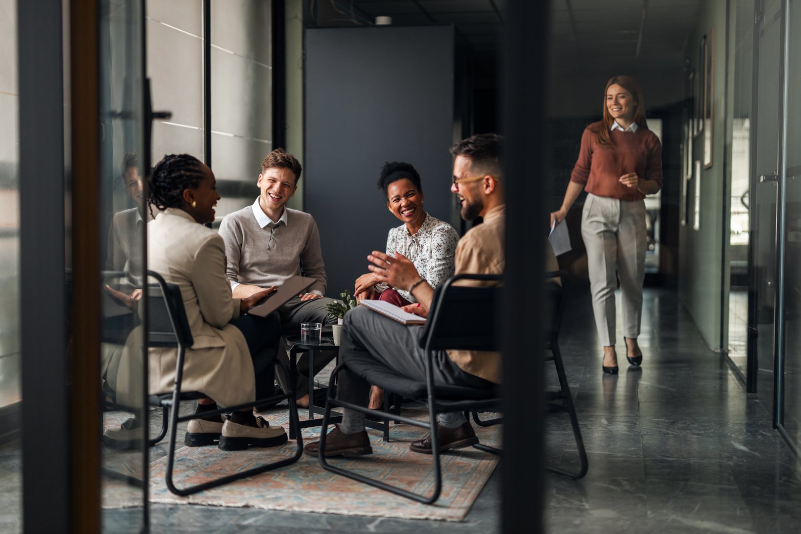 A diverse group of colleagues engaged in a friendly conversation in a workspace, showcasing teamwork and collaboration within a contemporary office environment.