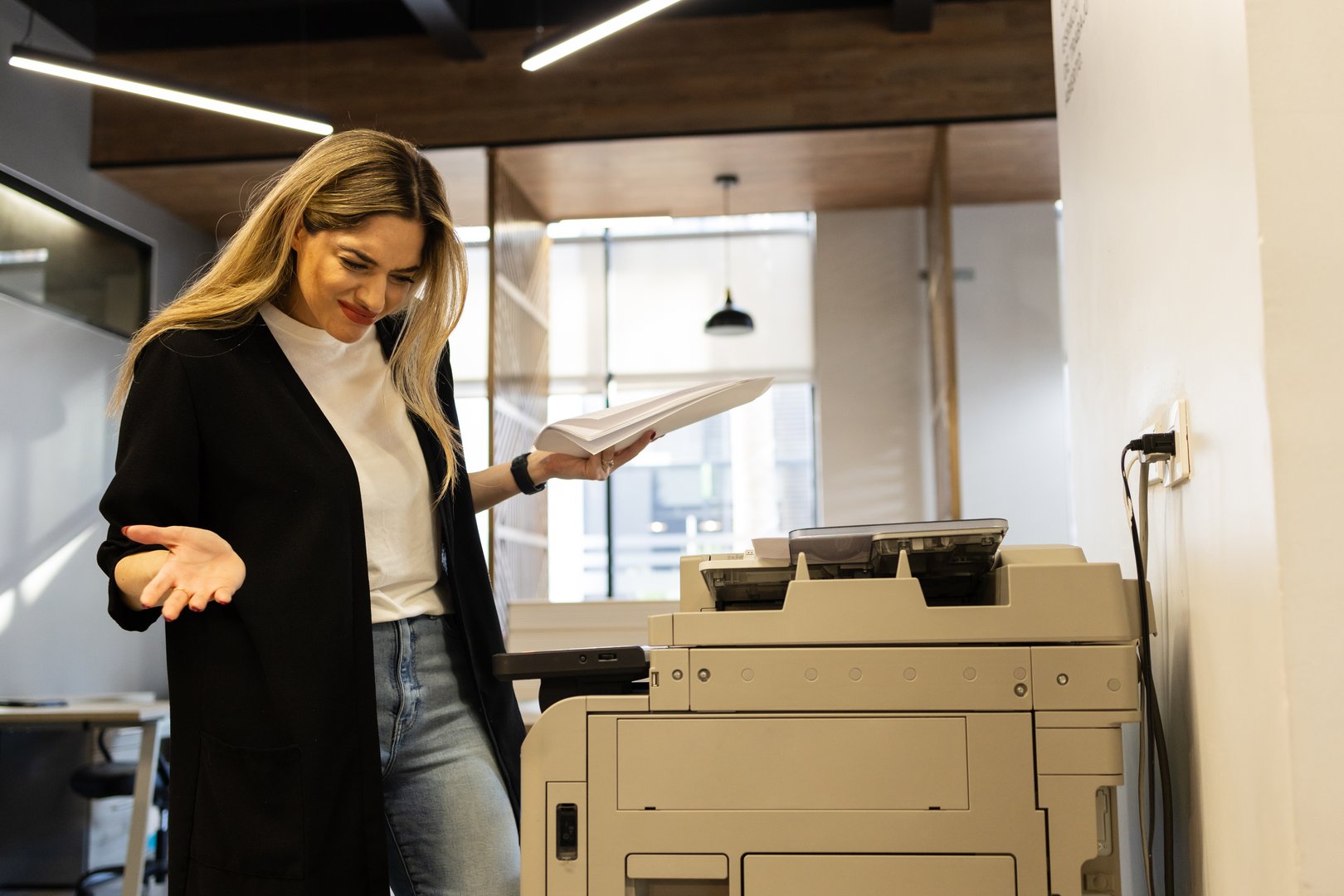Portrait of an upset woman looking puzzled while trying to make some copies in a photocopier