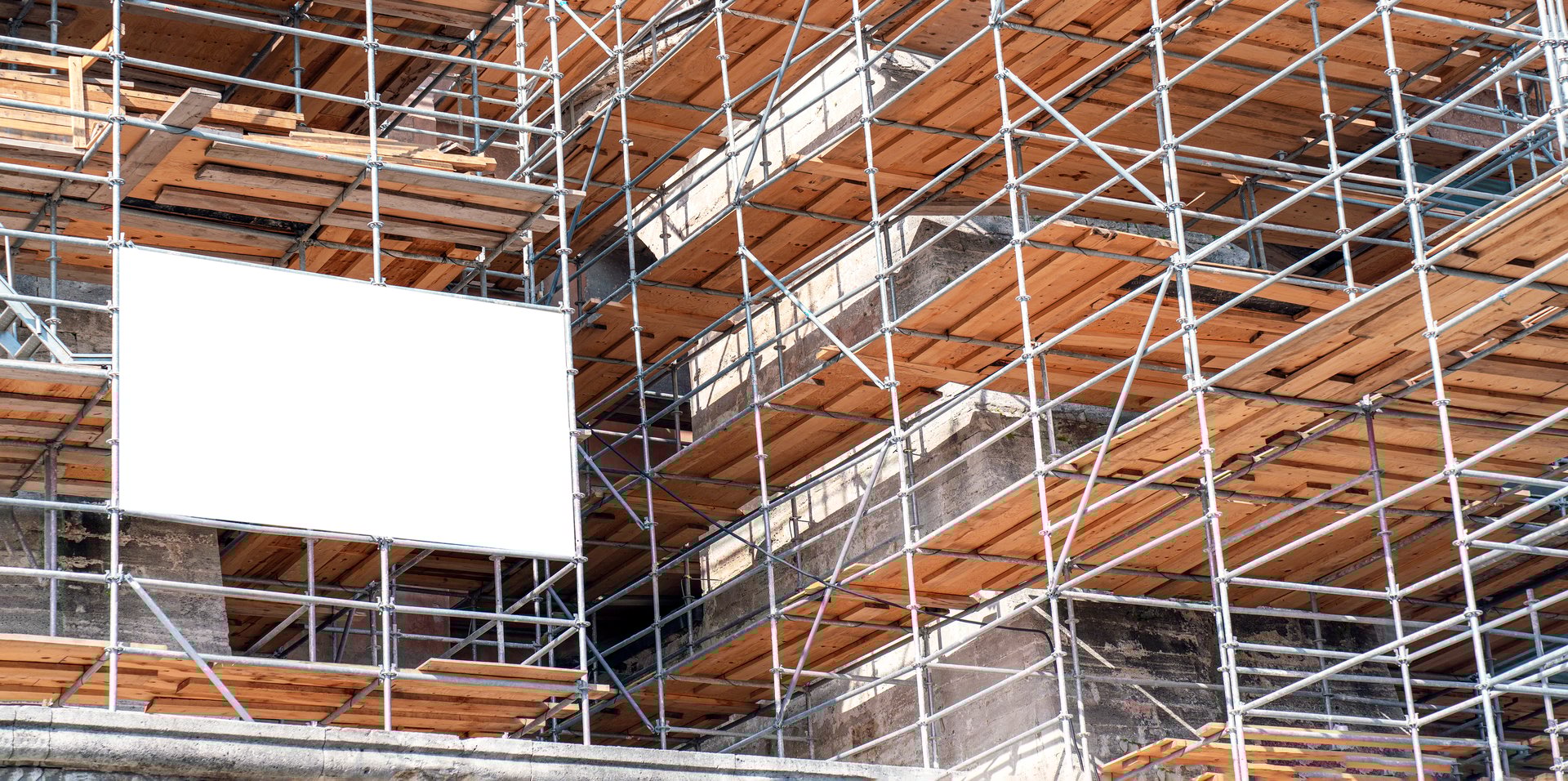 Metal scaffolding and large blank billboard covering old building during renovation or restoration