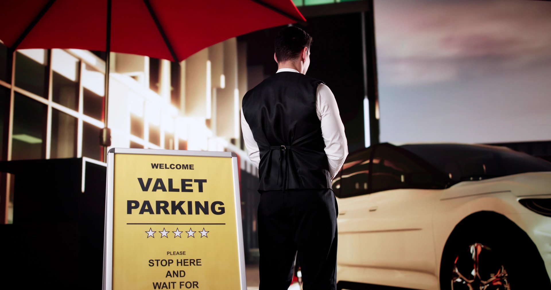 Rear View Of A Valet Standing In Front Of White Car