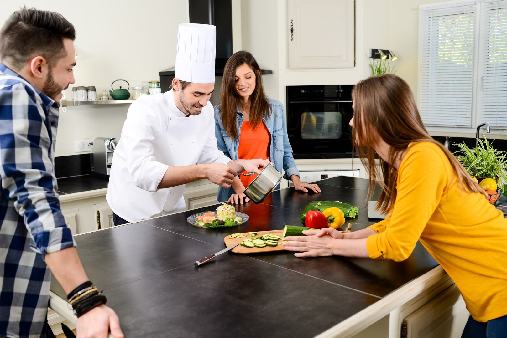 professional personal chef cook in customer's private kitchen house giving a cooking lesson to young people at home