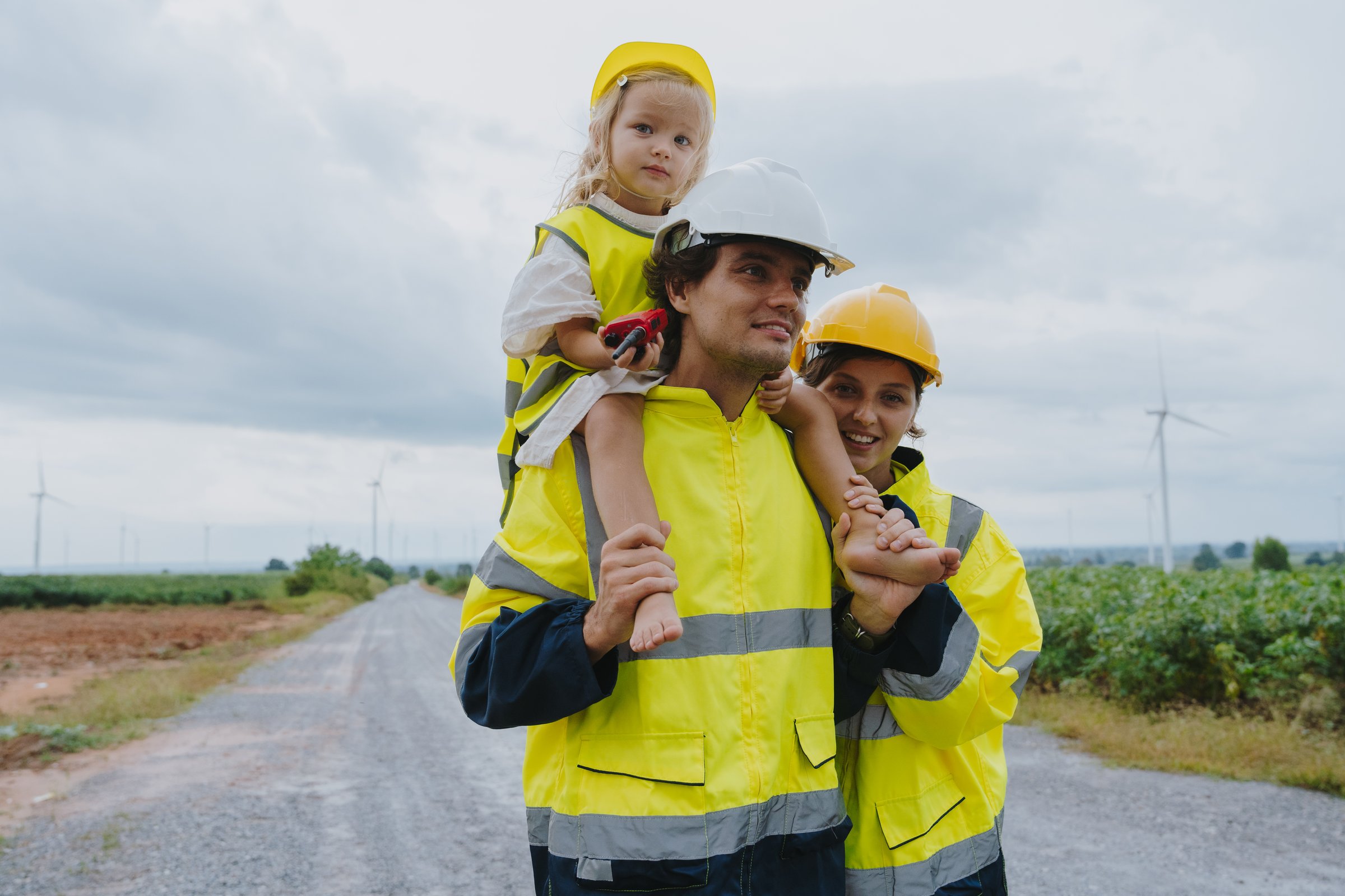 Family of father, mother and children in engineering uniforms working on wind farm turning to electricity. Alternative energy for clean energy concept.