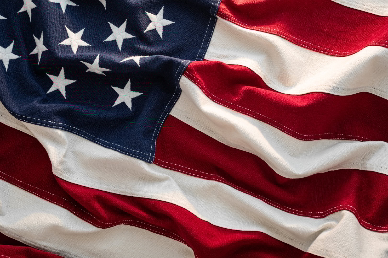 Close-up US Flag American flag waving in sunlight, red white stripes blue field stars.