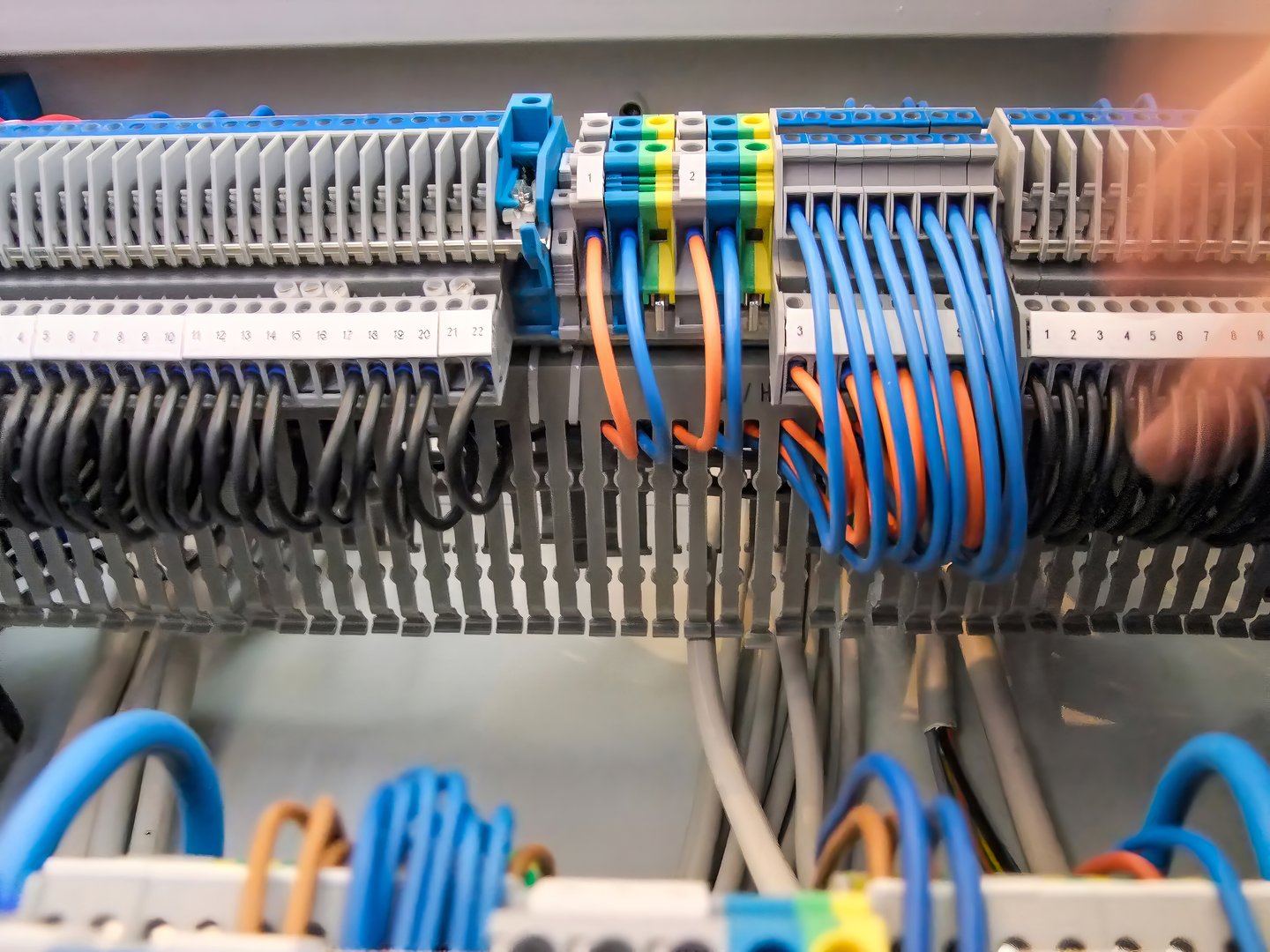 Wiring of an electrical panel shows an organized array of black, blue, and orange wires connected to terminal blocks in a control cabinet.