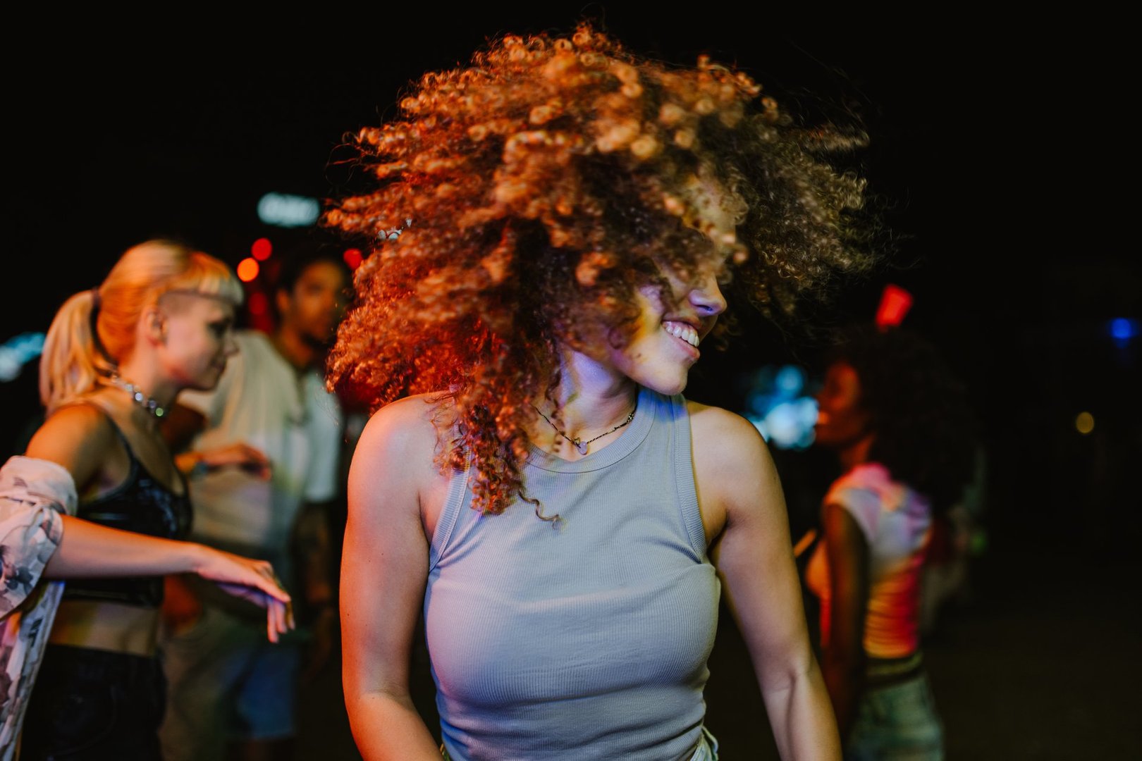 Carefree young woman enjoying music and dancing with friends at a vibrant nightclub party