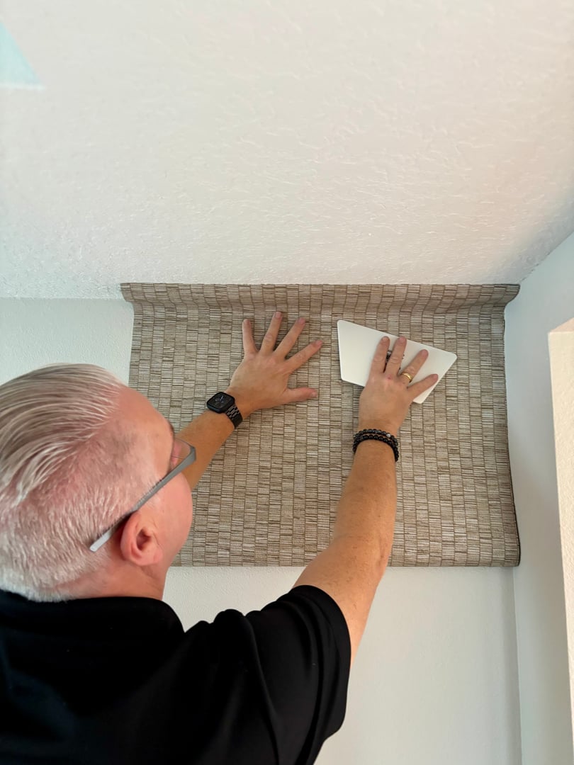 Worker attaching wallpaper. Man is putting up wallpapers on the wall. Home renovation concept