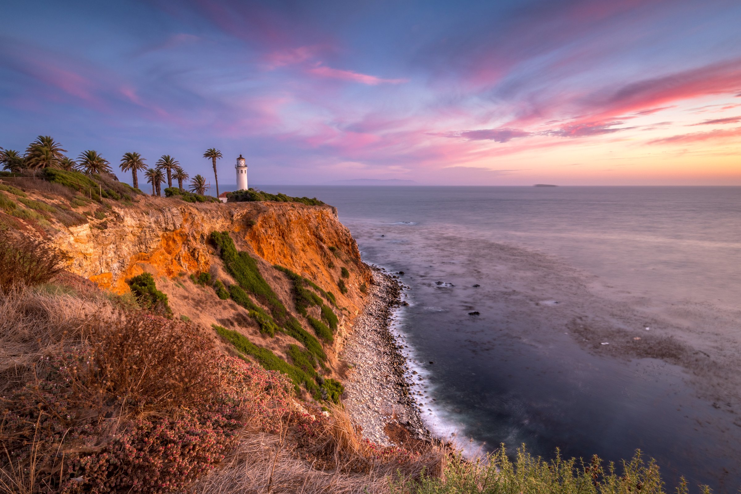 Golden hues illuminate the rugged coastline of Rancho Palos Verdes as the sun sets near the iconic Point Vicente Lighthouse.