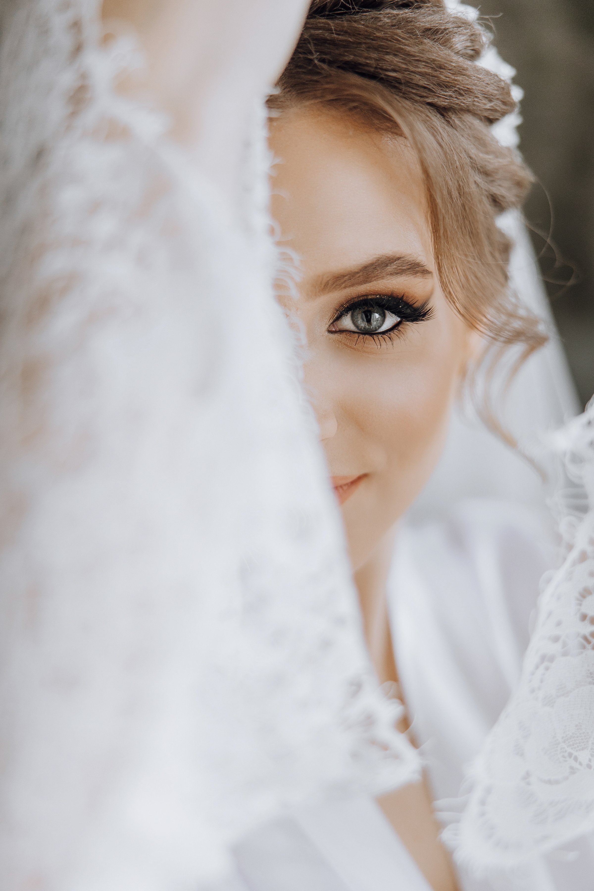 A woman with a veil over her face is wearing a white dress