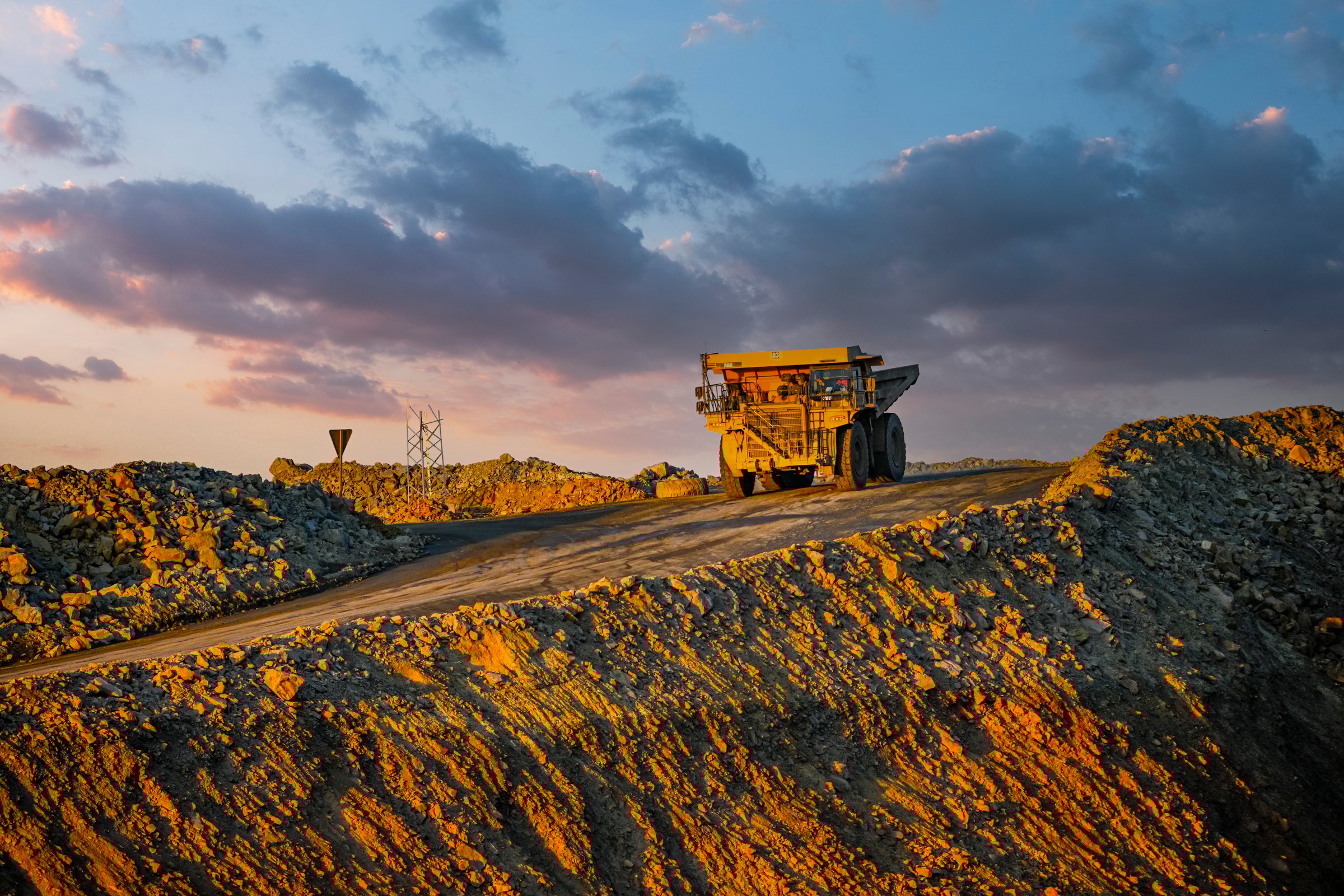 A large haul truck captured under the warm glow of sunset at a mining site, showcasing industrial activity