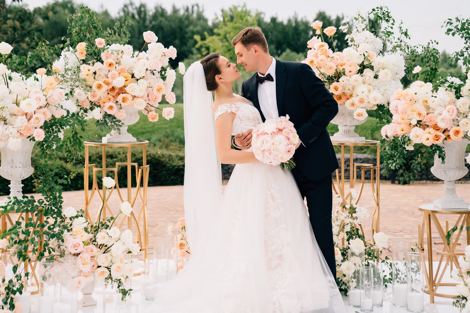 beautiful bride and groom in the wedding ceremony area of live white and pink flowers. decoration and organization of celebrations in the open air.