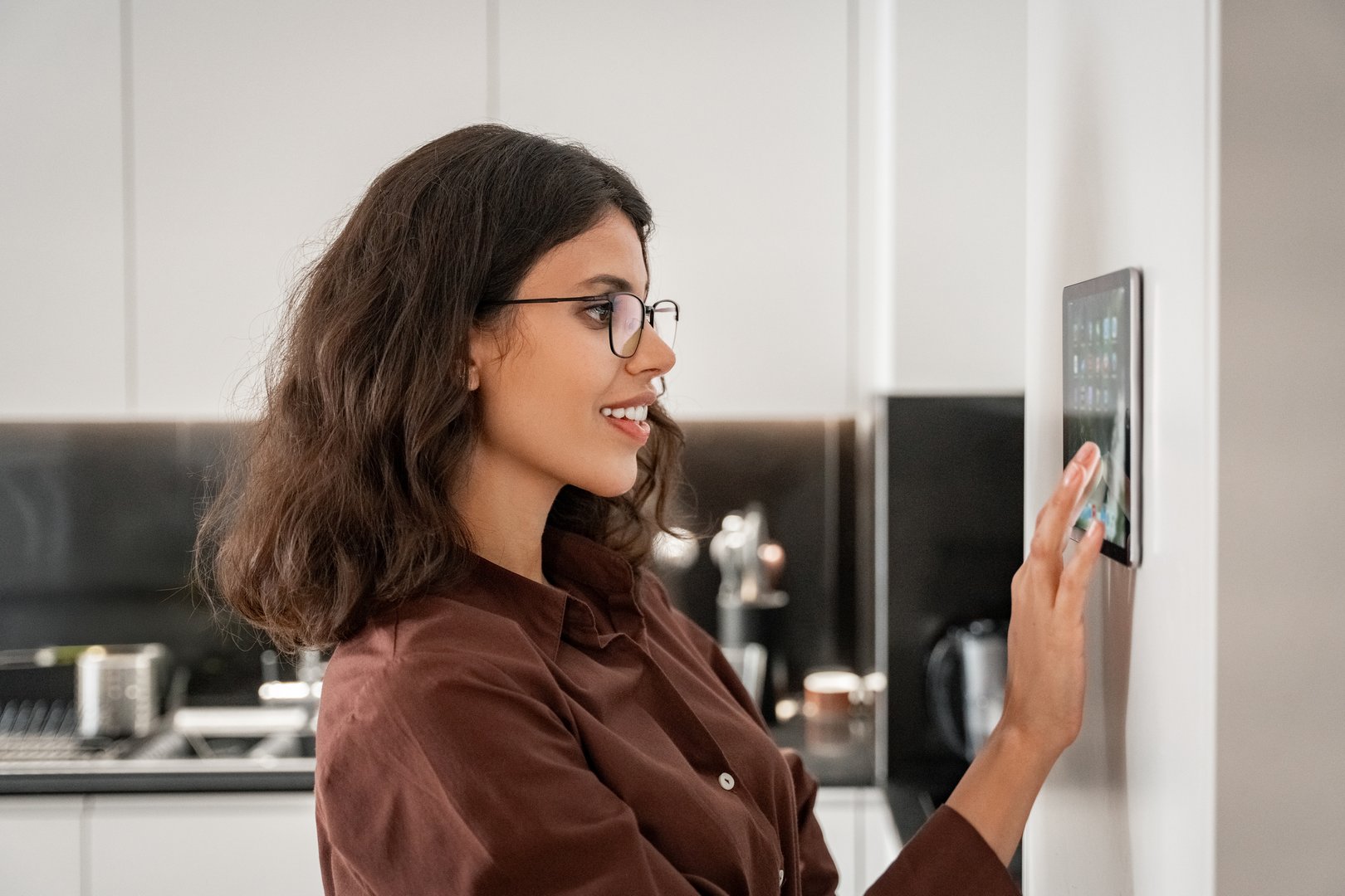 Closeup lady enjoy of new intelligence technologies. Smiling young woman using screen device gadget for remote control for air conditioning, cleaning housekeeping, touching tablet computer on wall.