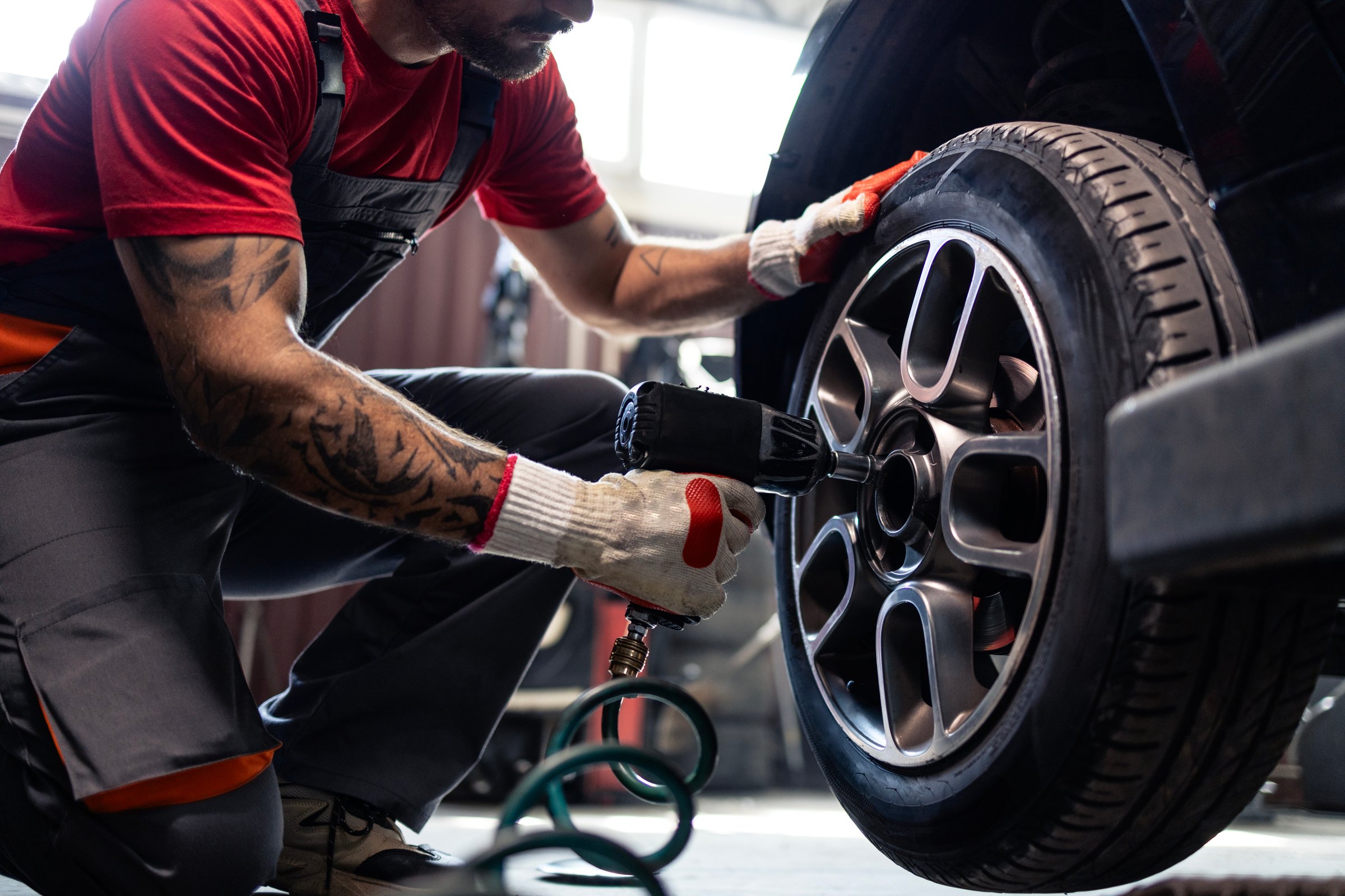 Tire shop mechanic using pneumatic tool