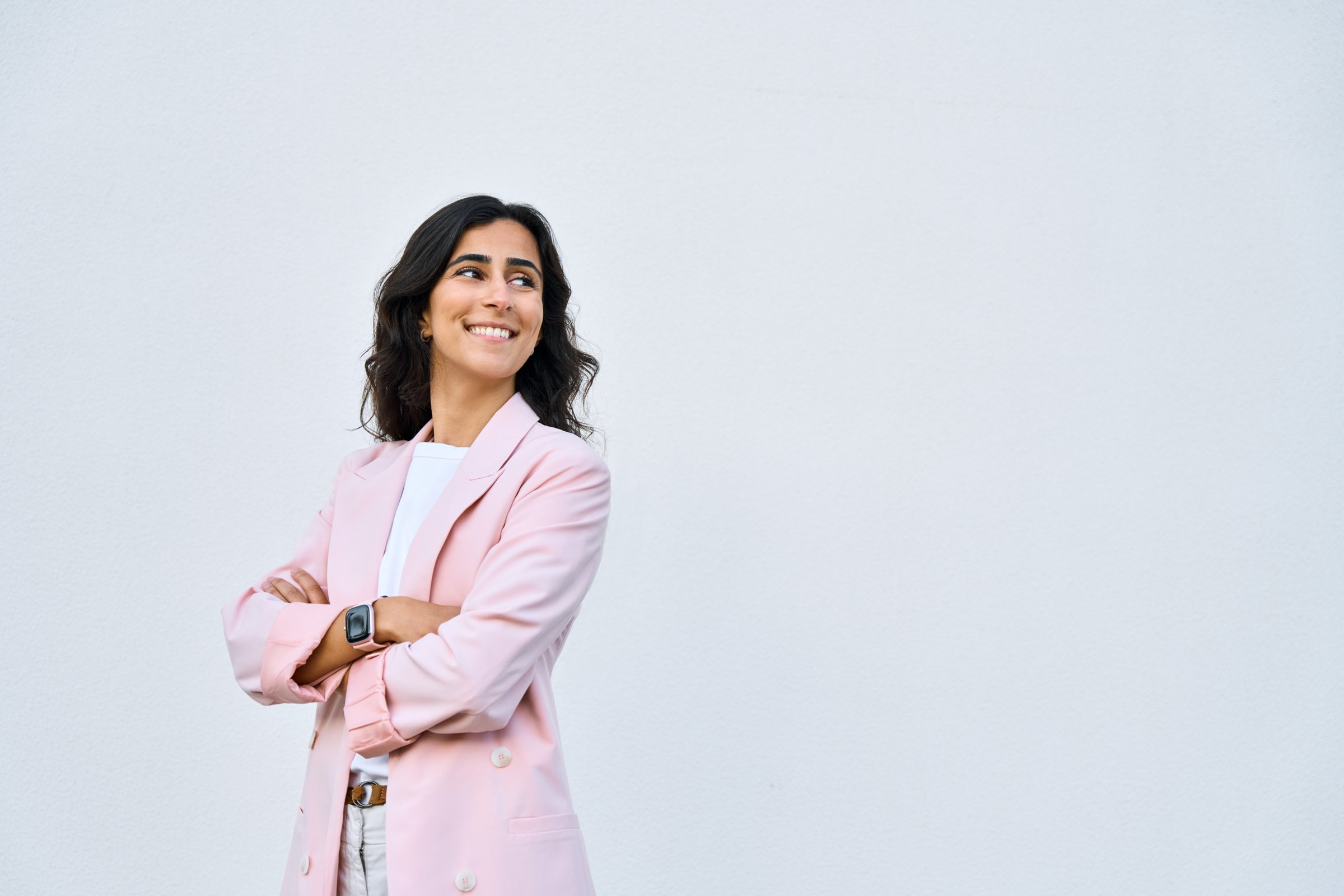 Portrait of middle eastern Israel businesswoman, business lady standing with crossed arms isolated on white background. Smiling 30s young Arabian or Indian woman in suit, looking aside at copy space