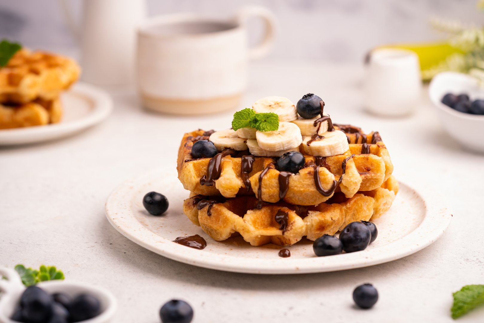 Tasty Belgian waffles with banana and fresh berries, cheese and chocolate on white table, close up. High quality photo