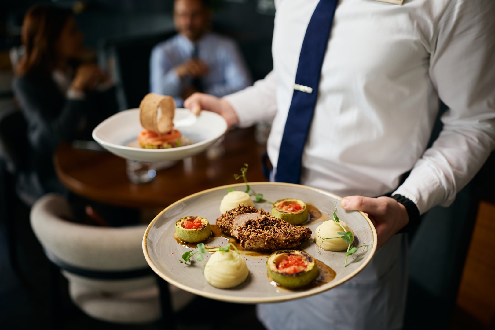Close up of waiter serving food during business lunch in a restaurant