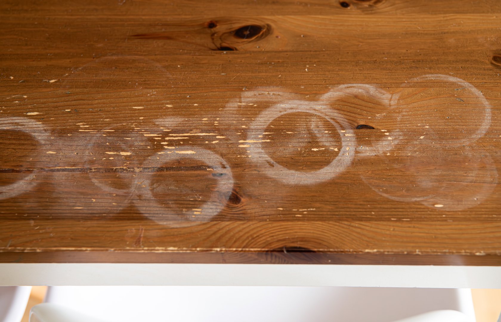 Ugly white round heat stains on home kitchen table, wood furniture ruined indoors home.