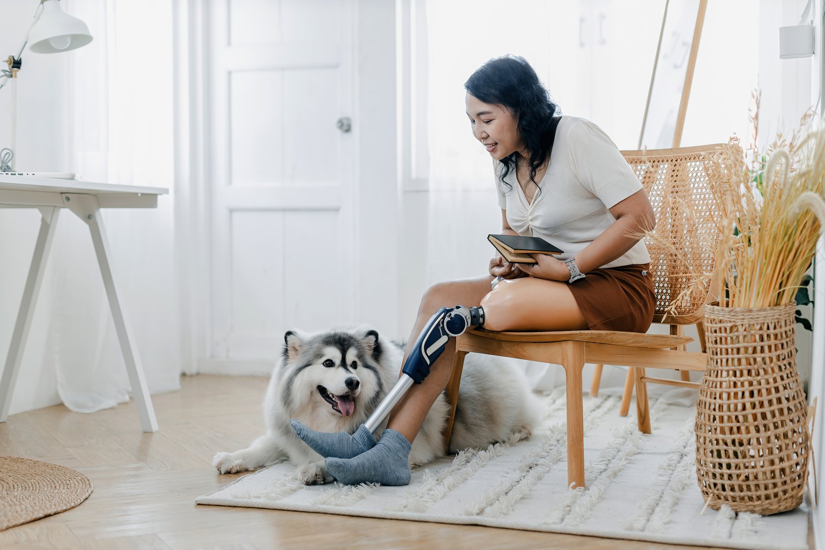 Woman with prosthetic leg sitting in chair near dog in at home. Woman sitting on chair with dog at home. couple with prosthetic leg sitting in living room.