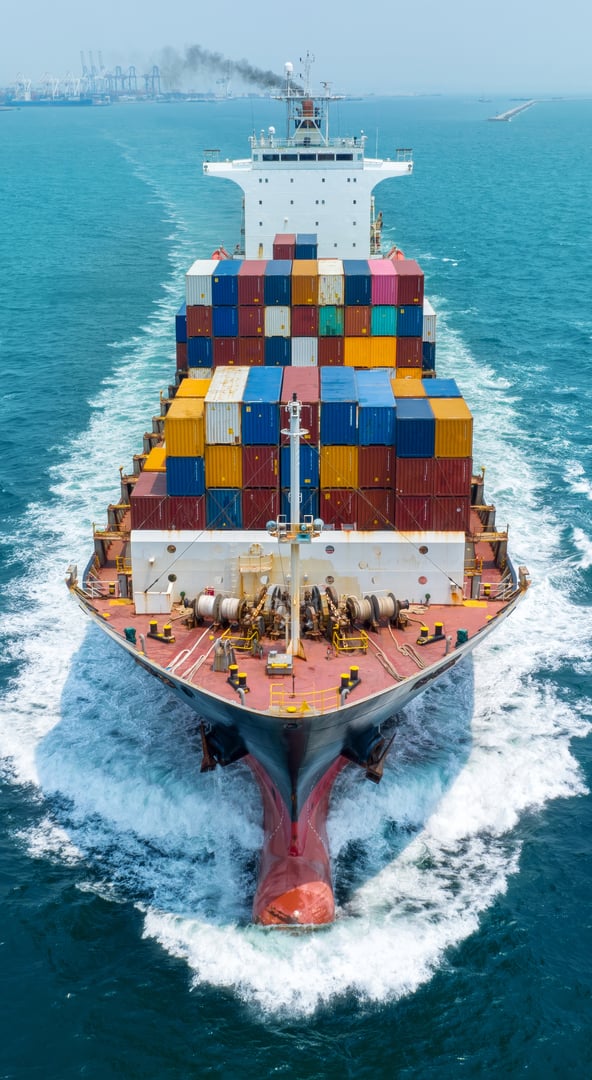 Aerial front view of cargo maritime ship with contrail in the ocean ship carrying container and running for export concept technology freight shipping by ship forwarder mast