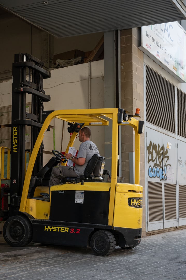 Barcelona, Spain – August 04, 2024: Detail of a yellow and black electric forklift entering the warehouse with a pallet. It's a Hyster 3.2