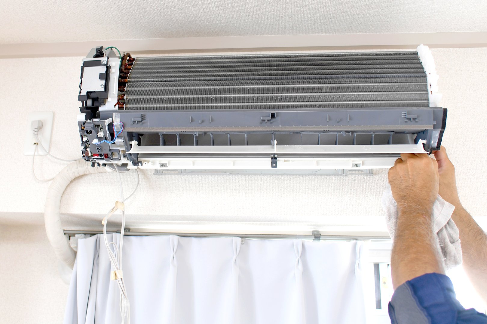The hands of a worker inspecting a residential air conditioner